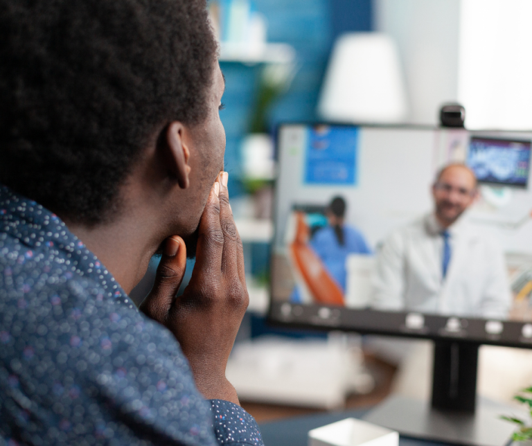 A man meeting with their doctor on a their computer during a telehealth appointment.